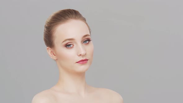 Studio portrait of young, beautiful and natural woman over grey background.