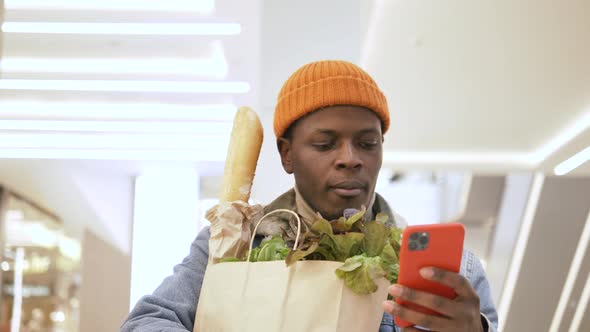 Black Man in Hat Holds Paper Bag with Healthy Products