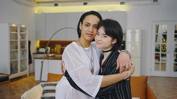 Portrait of Happy Lesbian Couple Embracing Each Other and Smiling in Living Room