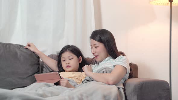 Portrait Happy Daughter playing smartphone with her mother on sofa in living room