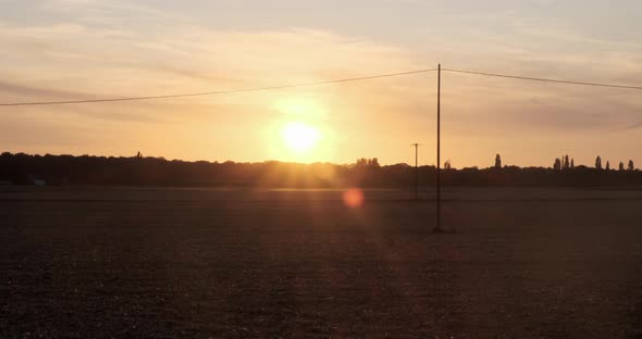 establishing shot of  fields in foreground as night falls in a backdrop of an orange sunset in norma