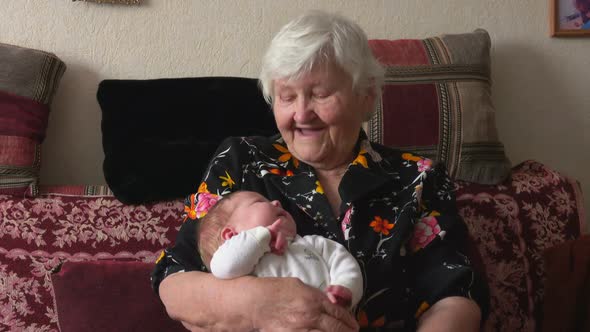 Grandmother Cradles Little Chubby Baby in Her Arms