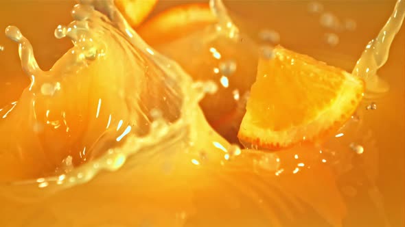 Slices of Orange Fall Into Orange Juice with Splashes