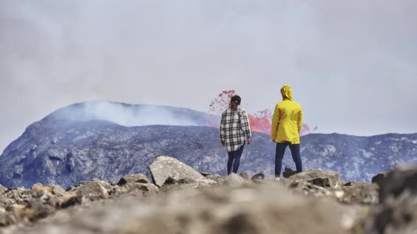 Shot of Erupting Volcano Releasing Magma As Two Adventurous Explorers Observe