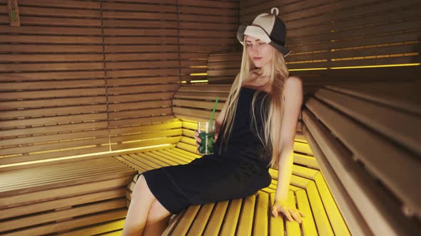 Nice Woman in Sauna Relaxing and Drinking Something
