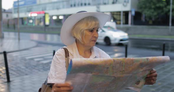 Senior Female Tourist Exploring Town with a Map in Hands. Looking for the Route