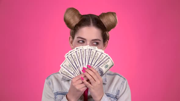 Teenager Holds Paper Bills and Winks. Pink Background. Slow Motion