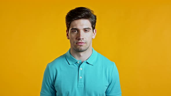 Portrait of Handsome Man in Blue T-shirt Looking To Camera. Guy in Studio on Bright Yellow