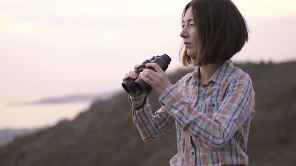 Beautiful Woman with Binoculars Looks Into the Camera