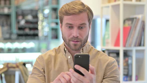 Portrait of Young Man Celebrating Success on Phone