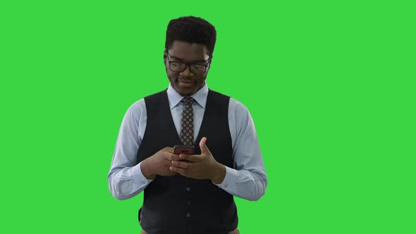 Happy Young African American Business Man Walking and Texting on Mobile Phone on a Green Screen