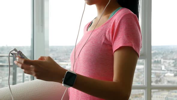 Woman in headphones using mobile phone at home 4k