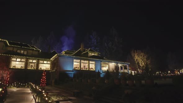 Wide shot of house decorated with Christmas lights and smoke coming from chimney, Night