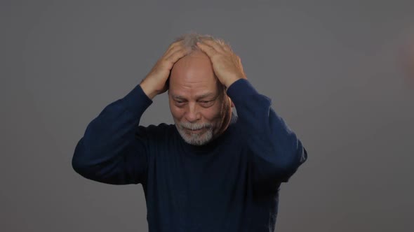 Depressed Man in Blue Pullover Runs Hands on Grey Hair