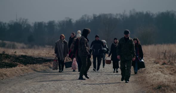 Soldiers Walking Ahead Of Refugee Group On Road