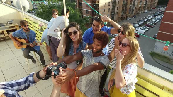 Happy people taking photos and laughing at the rooftop, musician playing guitar