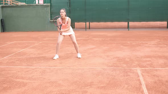 Professional Equipped Female Tennis Player Beating Hard the Tennis Ball with Racquet