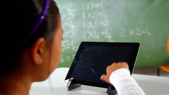 Schoolgirl using digital tablet in classroom at school