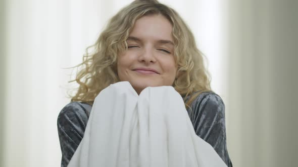 Closeup of Smiling Beautiful Blond Woman Smelling Fresh Clean Linen Looking at Camera with Satisfied