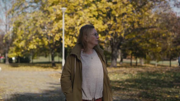 Caucasian senior woman walking alone at the park in autumn. Shot with RED helium camera in 4K