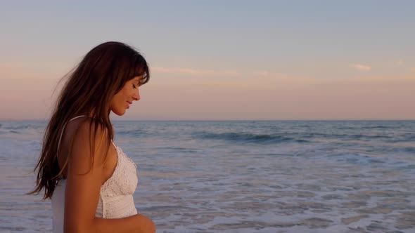 Beautiful woman in a white dress at the beach at sunset