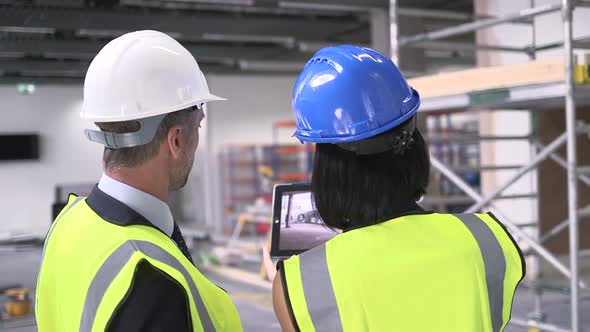 Man and woman discussing with digital tablet at construction site