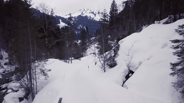 Aerial view of a small bridge over a creek in a snowy valley in the alps, Kleinwalsertal,Austria. Fl