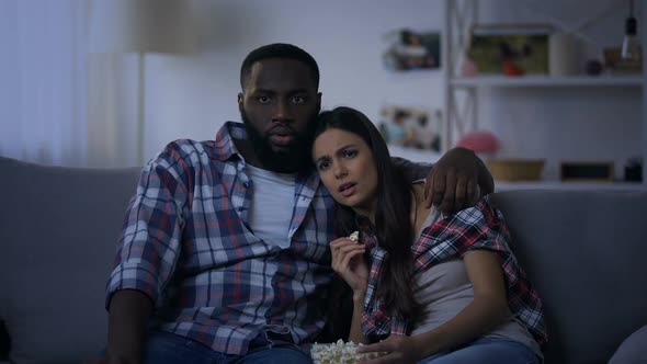 Emotional Mixed-Race Couple With Pop Corn Watching Horror Movie, Evening at Home
