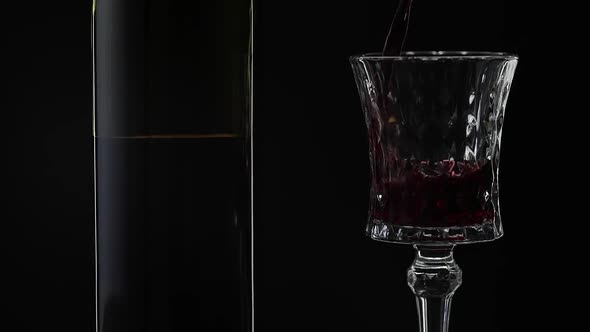 Rose Wine. Red Wine Pour in Wine Glass Over Black Background. Slow Motion