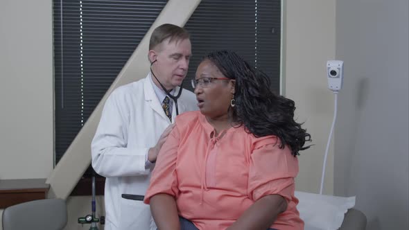 Doctor examining woman's breathing and heart rate.