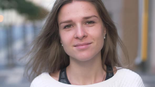 Young happy woman with beautiful green eyes and long hair walking in the street