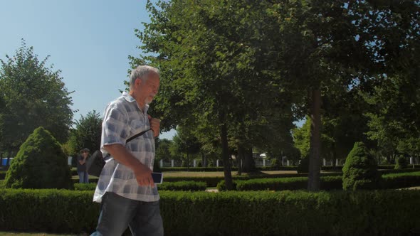 Grey Haired Old Man Walks Along Green Park Zone Against Sky