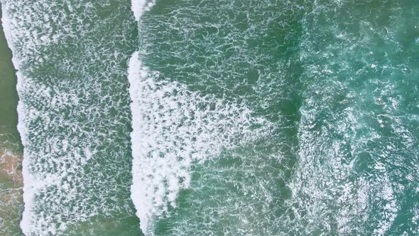 Drone view seascape on sunlight and wave crashing to the beach foaming .