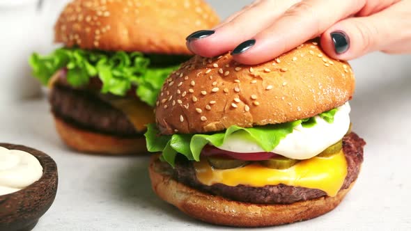 Cooking homemade beef burger with cheese, mayonnaise and vegetables