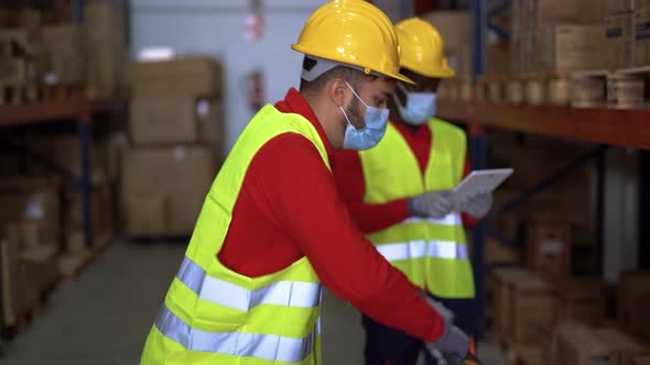 Worker men with forklift and tablet scanner working inside industrial warehouse