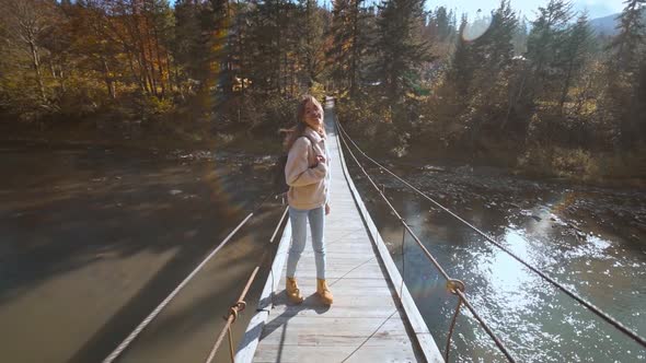 Slow Motion Portrait of Happy Beautiful Young Woman Tourist Standing on Wooden Suspension Bridge