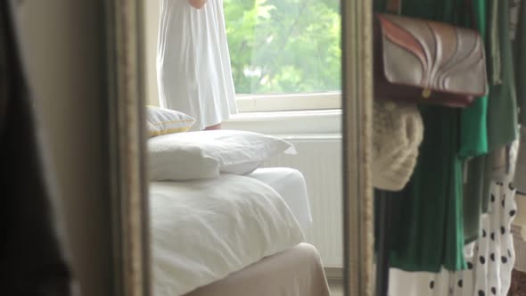 Female drinking tea in front of window reflected in mirror