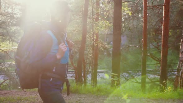 Girl Tourist in a Backpack Walking in the Park at Sunset