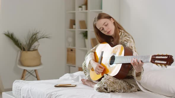 Happy Woman in Pajama Playing Guitar at Home