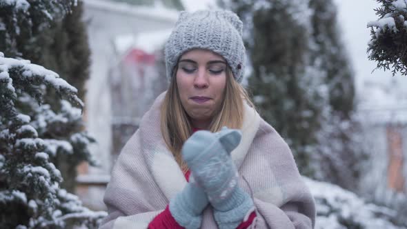 Portrait of Happy Young Caucasian Woman in Winter Hat and Gloves Standing Outdoors. Smiling Charming