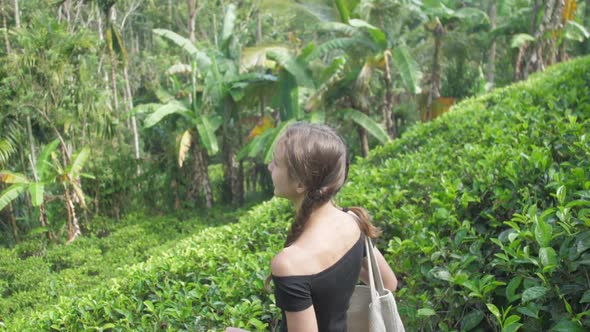 Young Woman in Black T-shirt Walks Along Large Plantation