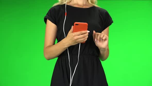 Girl Goes in Headphones and Texting with Red Smartphone, Close Up. Green Screen