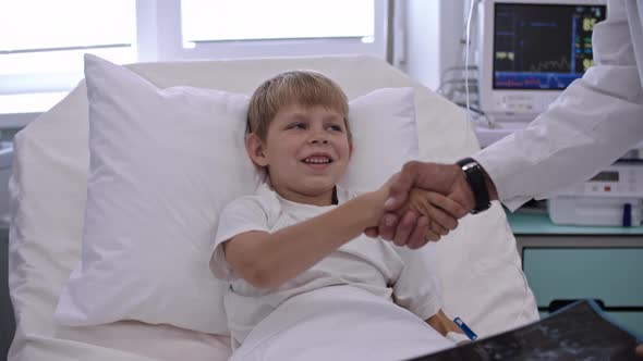 Cute Boy Shaking Hands with Doctor in Hospital Ward