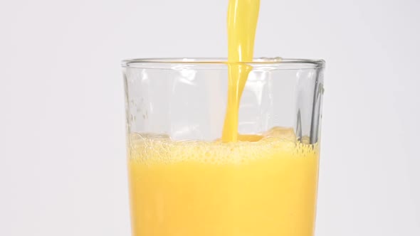 Pouring fresh orange juice in glass over white