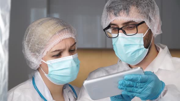 Medical Team of Doctors in Protective Masks Discuss Patients Diagnosis Covid19 on Digital Tablet in