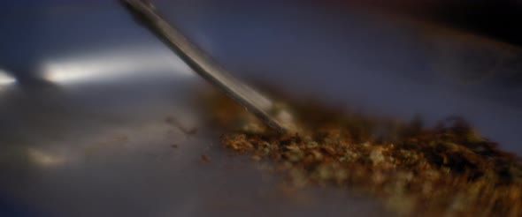 Trimming marijuana with scissors to roll a joint. Close up of weed being cut up.