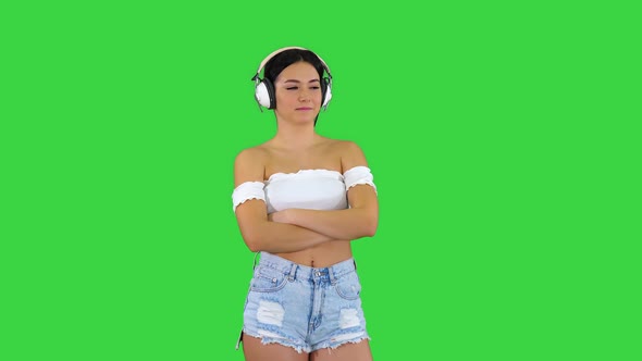 Young Hispanic Woman Wearing Headphones Serious Face Thinking on a Green Screen, Chroma Key.