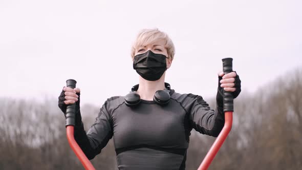 The Sporty Woman in a Protective Mask Is Doing Workout in a Park