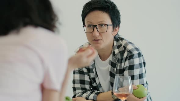 Young Lesbian Couple are Talking and Eating at Table in Home Kitchen During Selfisolation Rbbro