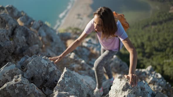 Slow Motion Top View Woman Hiker Rock Climber Climbs Up on Cliff on Mountain Over Beautiful Sea